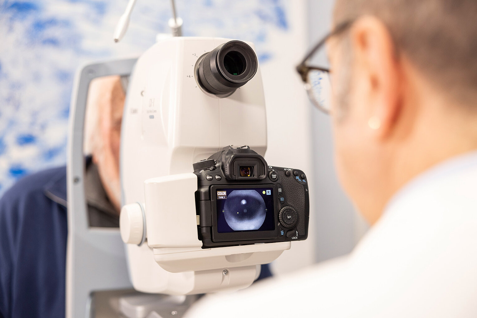 Augenuntersuchung mit Kameraunterstützung Nahaufnahme eines Augenuntersuchungsgeräts, das mit einer Kamera verbunden ist, die die Augen des Patienten aufnimmt.